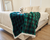 White Scottish Terrier Dog resting on Green Plaid Blanket on corner of Bed